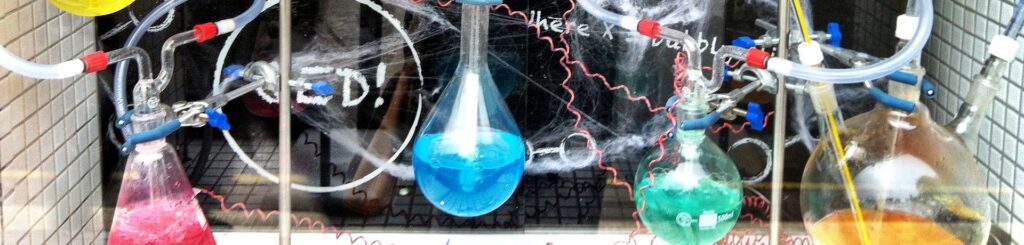 Experimento de química que muestra un proces de líquidos de colores brillantes en differente matraz y todos concetados por nas mangas.