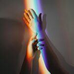 La perspectiva artística de la luz y el color en la imagen se ven dos manos y el espectro de color producido por un prisma