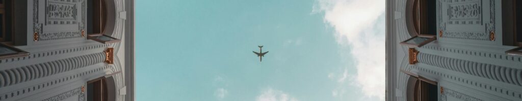 El cénit es el punto directamente sobre el observador. en la imagen se ve un avión en el cielo justo al pasar arriba de un área interior de un edificio con muchas ventanas.