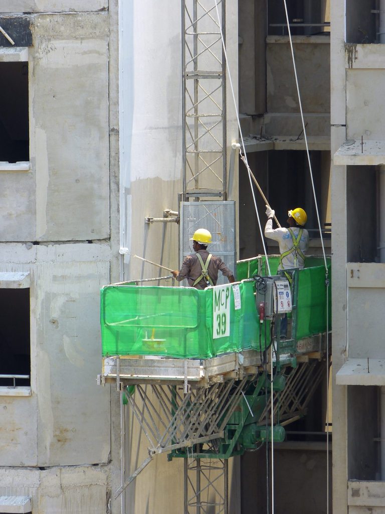 Constructores utiliando un elevador para pintar.