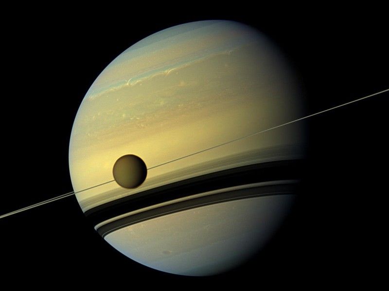 Saturno y su luna Titan orbitando alrededor del planeta. Imagen capturada por la misión Cassini de NASA.